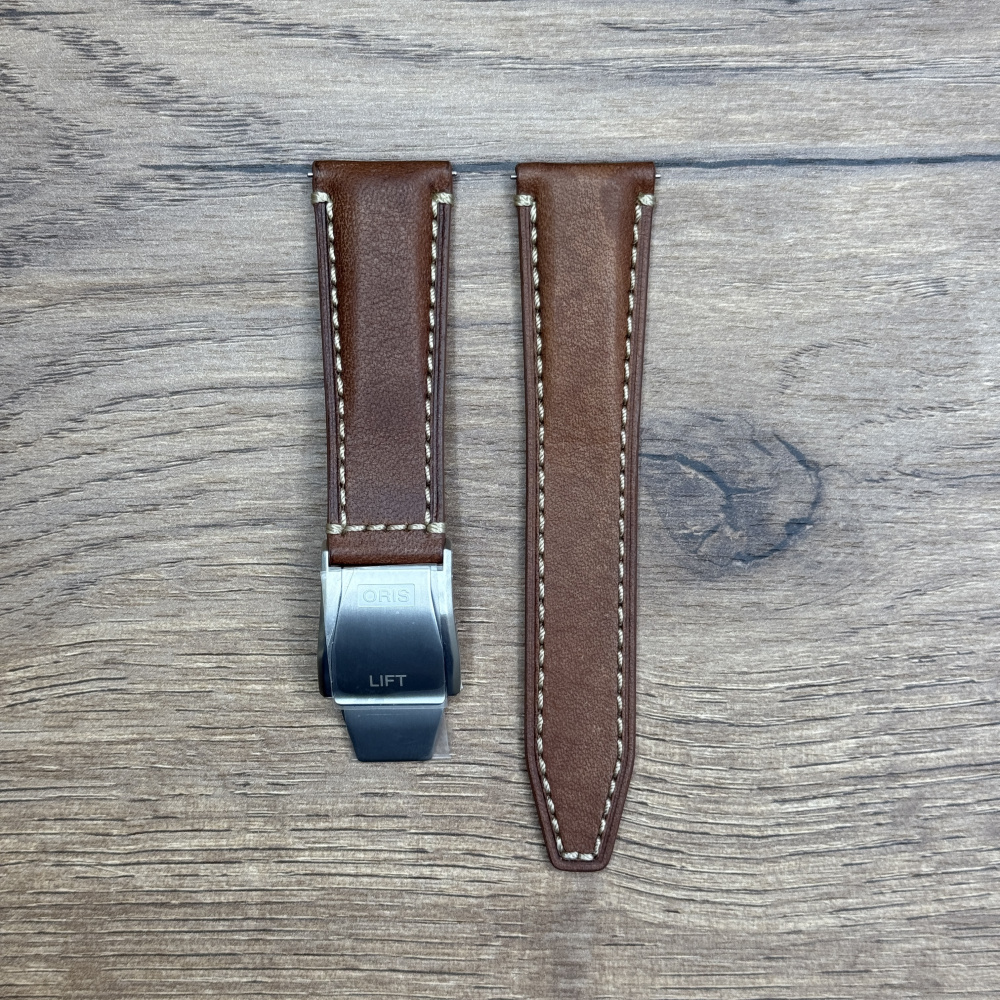 Ремешок для часов Oris коричневого цвета, белая строчка, с клипсой из нержавеющей стали Кожаные ремешки - стильные, надёжные и долговечные, способные составить достойную пару часам со стальным корпусом или часам из титана. Аксессуары из кожи не рекомендуется использовать в воде. У нас присутствуют только высококачественные материалы и оригинальный товар от производителя.