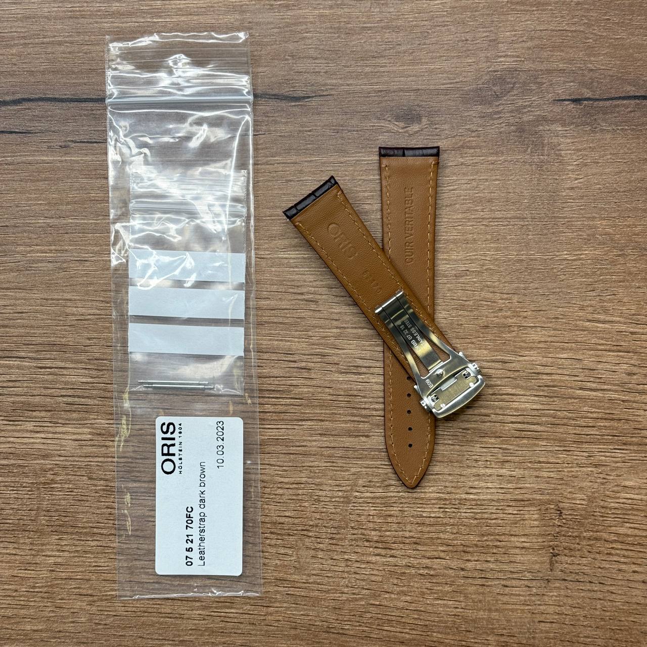 Ремешок для часов Oris из кожи теленка, темно-коричневый, со стальной клипсой Кожаные ремешки - стильные, надёжные и долговечные, способные составить достойную пару часам со стальным корпусом или часам из титана. Аксессуары из кожи не рекомендуется использовать в воде. У нас присутствуют только высококачественные материалы и оригинальный товар от производителя